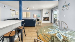 A modern living room with a glass dining table, a fireplace, and a view of the outside. - Balboa Hideaway w/ Patio next to Pier, Fun Zone, (Newport Beach)
