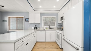 A modern kitchen with white cabinetry, a wooden floor, and a built-in oven. - Balboa Hideaway w/ Patio next to Pier, Fun Zone, (Newport Beach)