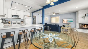 A modern kitchen with white cabinets, a central island, and bar stools. - Balboa Hideaway w/ Patio next to Pier, Fun Zone, (Newport Beach)