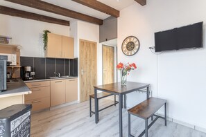 Cozinha moderna com armários de madeira, uma mesa de jantar com bancos, um relógio e uma televisão de tela plana.