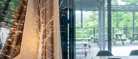 Blick auf ein Restaurant mit Außenbereich, einer dekorativen Lichtinstallation und einer Glaswand.
