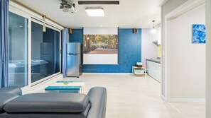 Enjoy a spacious living area with a sliding glass door leading to a balcony, compact kitchenette, and seating area with sofa.