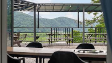 A terrace with tables and chairs, overlooking a mountainous landscape.