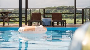 A pool with a floating ring, two chairs, and a view of a green landscape. - Yeongwol You and I Spa Pension (Yeongwol)