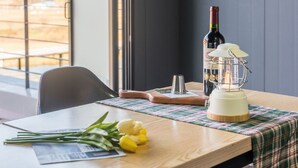 A wooden table with a plaid tablecloth, a bottle of wine, a candle, and a bouquet of yellow flowers. - Yeongwol You and I Spa Pension (Yeongwol)