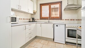Eine Küche mit weißen Schränken, einer Mikrowelle, einer Kaffeemaschine, einem Geschirrspüler und einem Backofen.