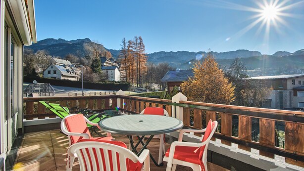 Un balcon avec une table et des chaises, donnant sur un paysage montagneux.