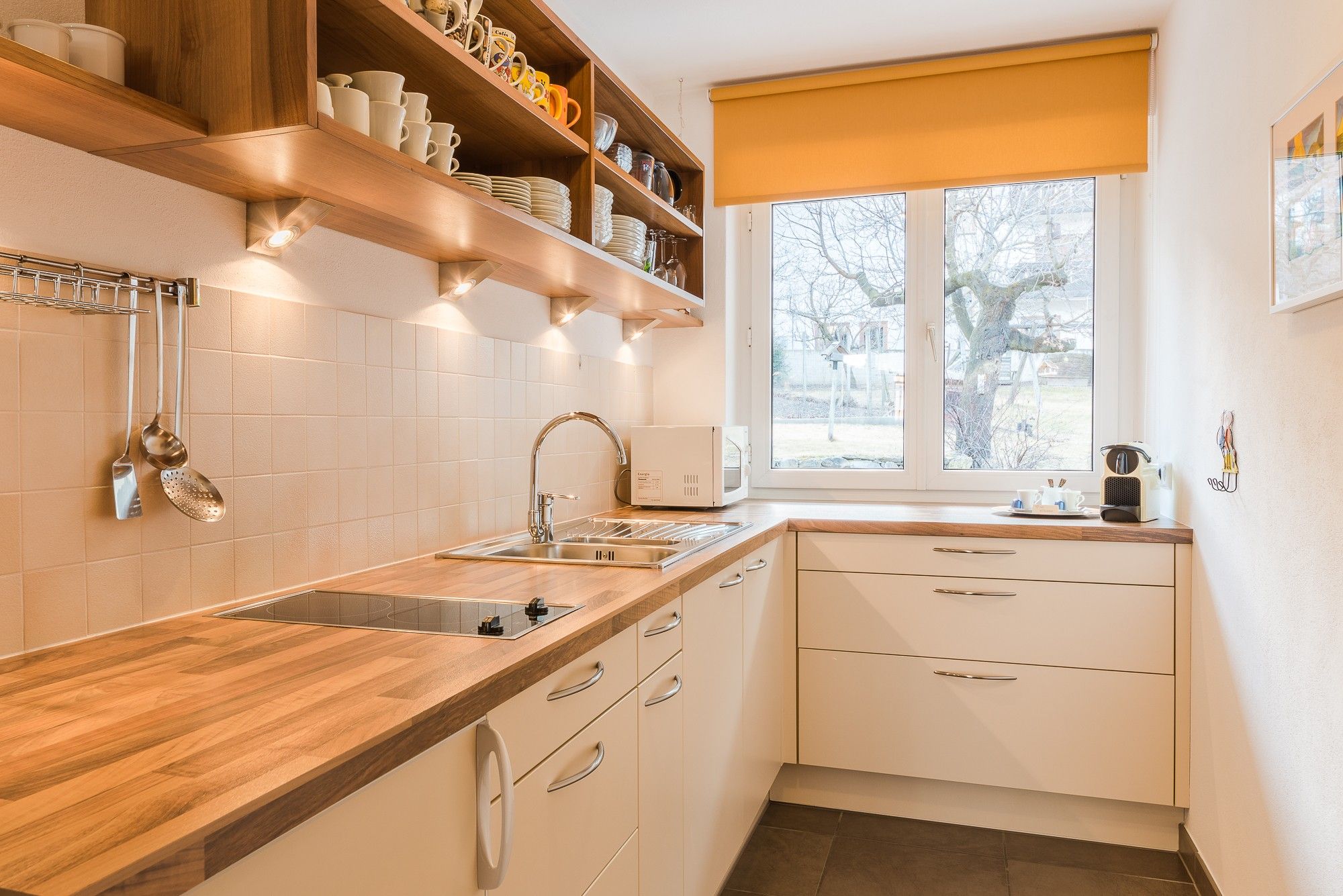 Una cucina con un piano di lavoro in legno, un lavello e una finestra vista alberi.