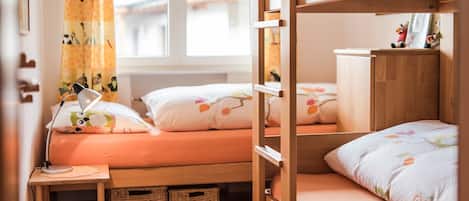 A cozy bedroom with bunk beds, a bedside lamp, and a window with curtains.