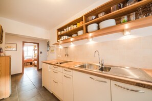 Een moderne keuken met een houten aanrecht, een roestvrijstalen spoelbak en inbouwplanken boven het aanrecht.