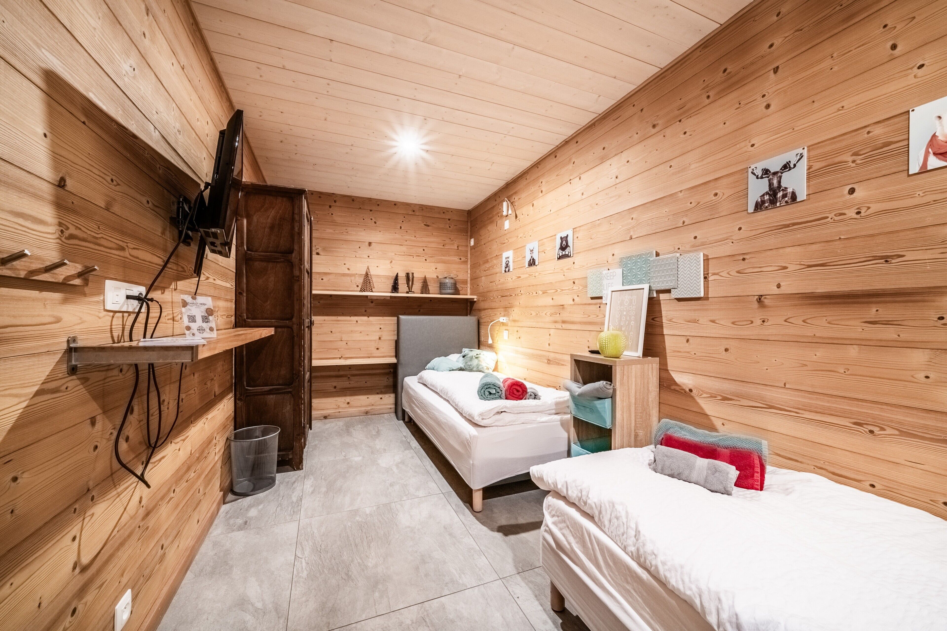 A wooden-paneled room with a bed, bedside table, and wall-mounted shelf.