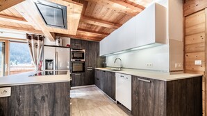 A modern kitchen with wooden ceiling beams, a built-in oven, and a dishwasher. - Chalet 'Heidi - Chatel' with Mountain View, Private Terrace and Wi-Fi (Châtel)