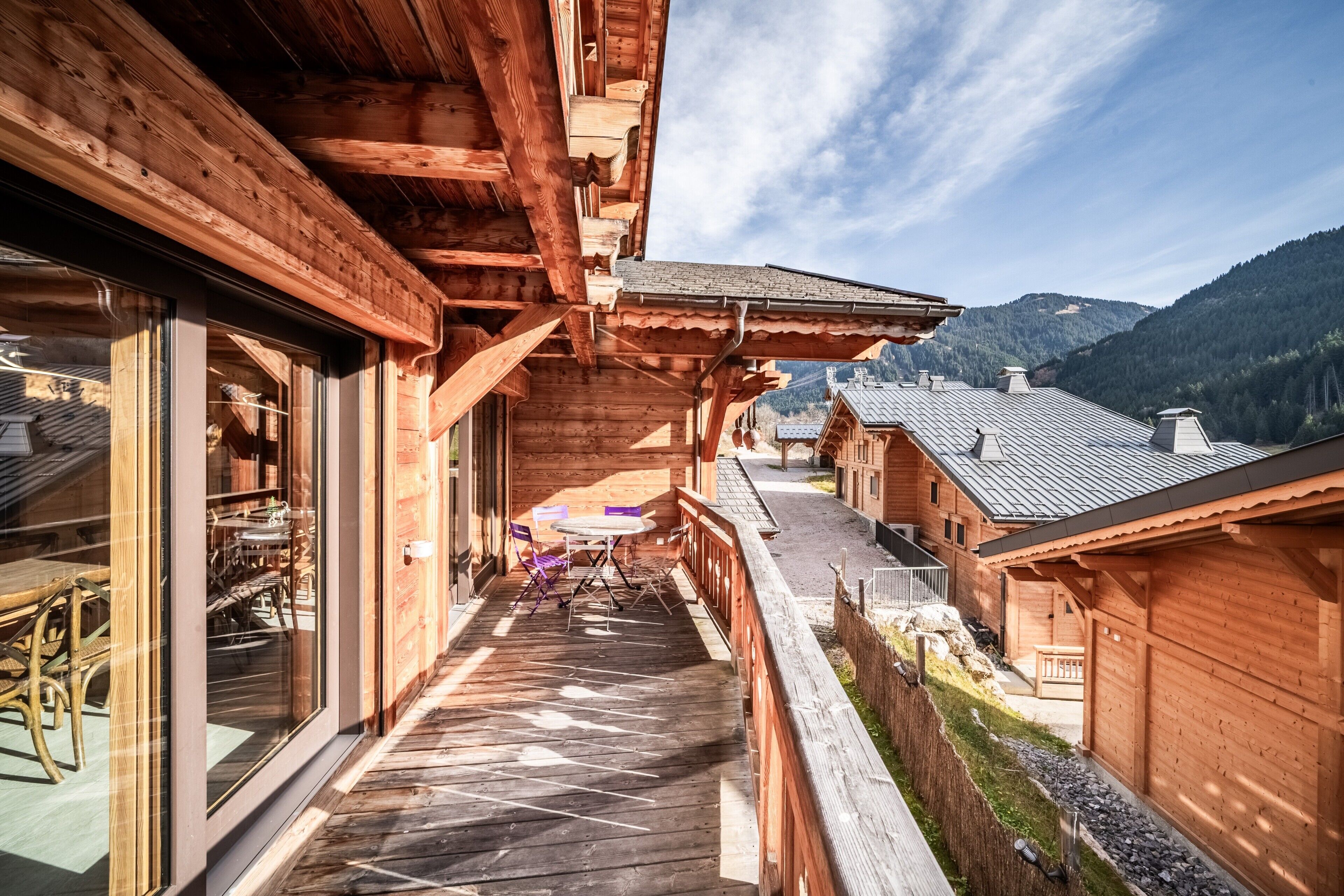 A wooden chalet with a balcony, a dining area, and a view of the mountains.