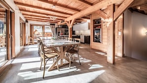 A spacious dining area with a long wooden table and chairs, wooden beams on the ceiling, and a view of the outside. - Chalet 'Heidi - Chatel' with Mountain View, Private Terrace and Wi-Fi (Châtel)