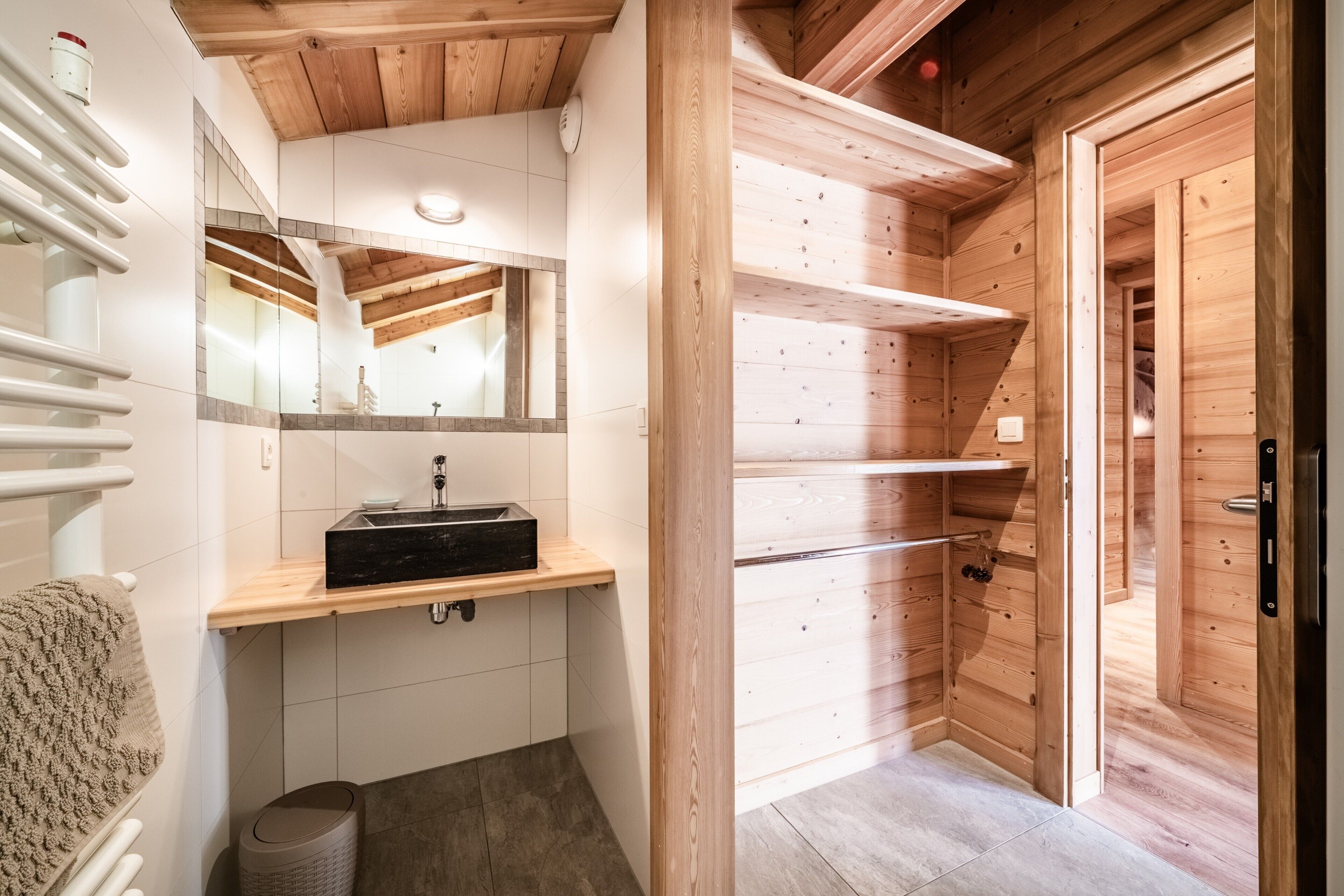 Ein Holzblockhaus-Interieur mit einem Badezimmer, das ein Waschbecken, einen Spiegel und einen Handtuchhalter zeigt.