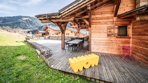 A wooden cabin with a deck, outdoor seating, and a view of the surrounding landscape. - Chalet 'Heidi - Chatel' with Mountain View, Private Terrace and Wi-Fi (Châtel)