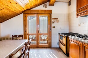 Een keuken met houten kastjes, een fornuis en een eethoek met een tafel en stoelen.
