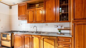 Une cuisine avec des meubles en bois, un plan de travail en granit, un évier en acier inoxydable et une cuisinière intégrée.