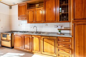 Una cocina con gabinetes de madera, encimera de granito, pileta de acero inoxidable y estufa integrada.