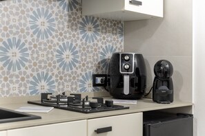 A kitchen with a coffee maker, a kettle, and a small appliance on the counter.