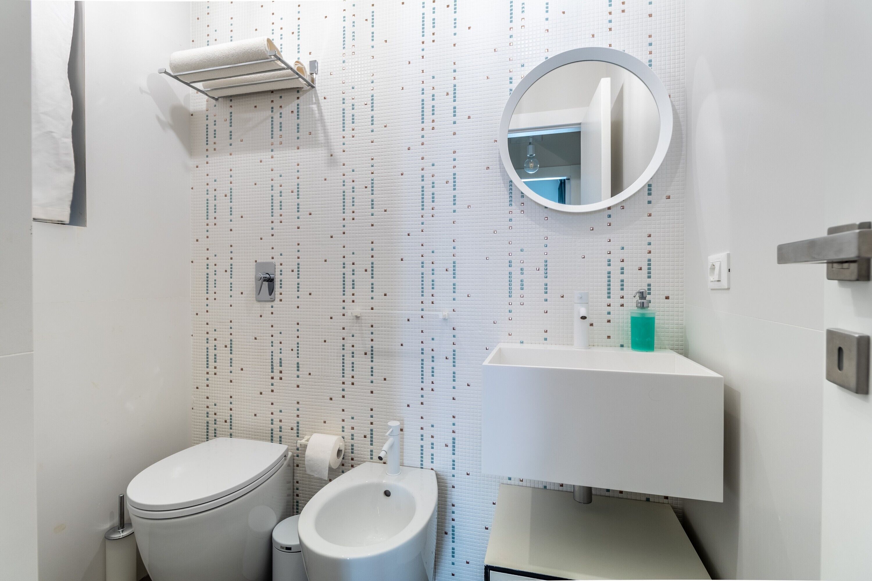 A modern bathroom with a toilet, bidet, and a sink with a mirror.