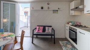 A kitchen with a bench, a table, and a view through a glass door. - Holiday Home "La Dimora della Luna" with Sea View, Terrace and Wi-Fi (Pozzallo)