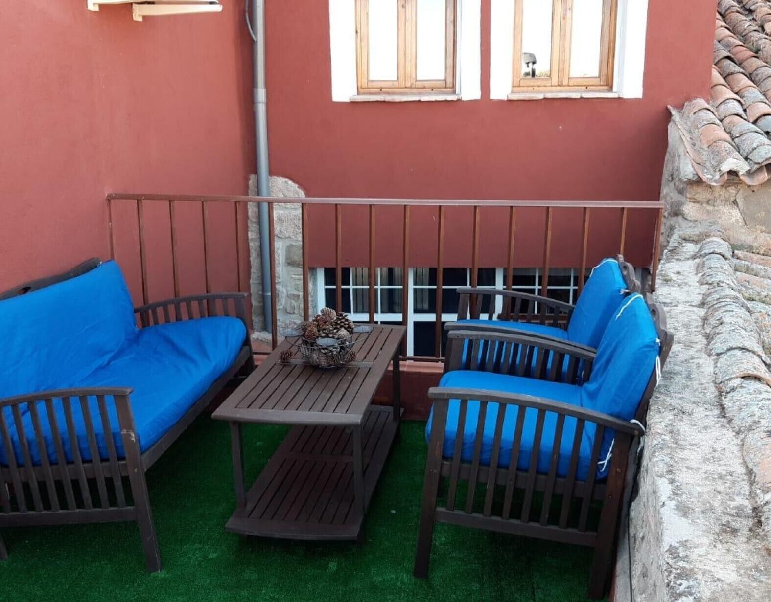 Une terrasse avec deux chaises bleues dotées de coussins, une petite table et une rambarde en métal.