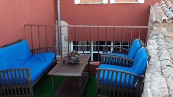 Une terrasse avec deux chaises bleues dotées de coussins, une petite table et une rambarde en métal.