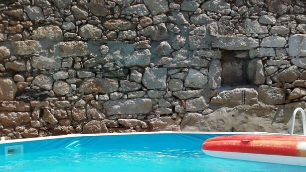 Una piscina con uno sfondo a muro in pietra.