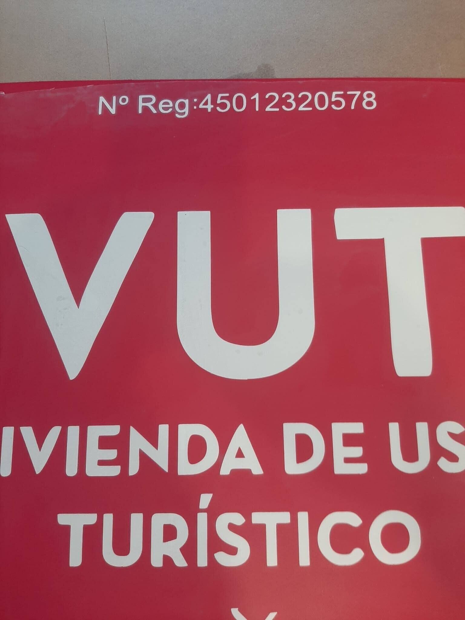 Un panneau rouge avec du texte blanc indiquant : « VUT », « IVIENDA DE US » et « TURÍSTICO ».