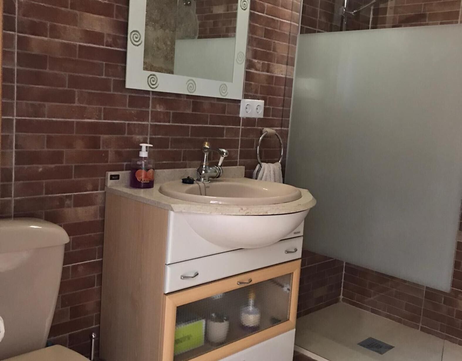 Un baño con lavamanos, espejo y ducha.