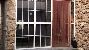 Un edificio in pietra con un'ampia finestra, un muro rosso e un lanternino nero sul terreno.
