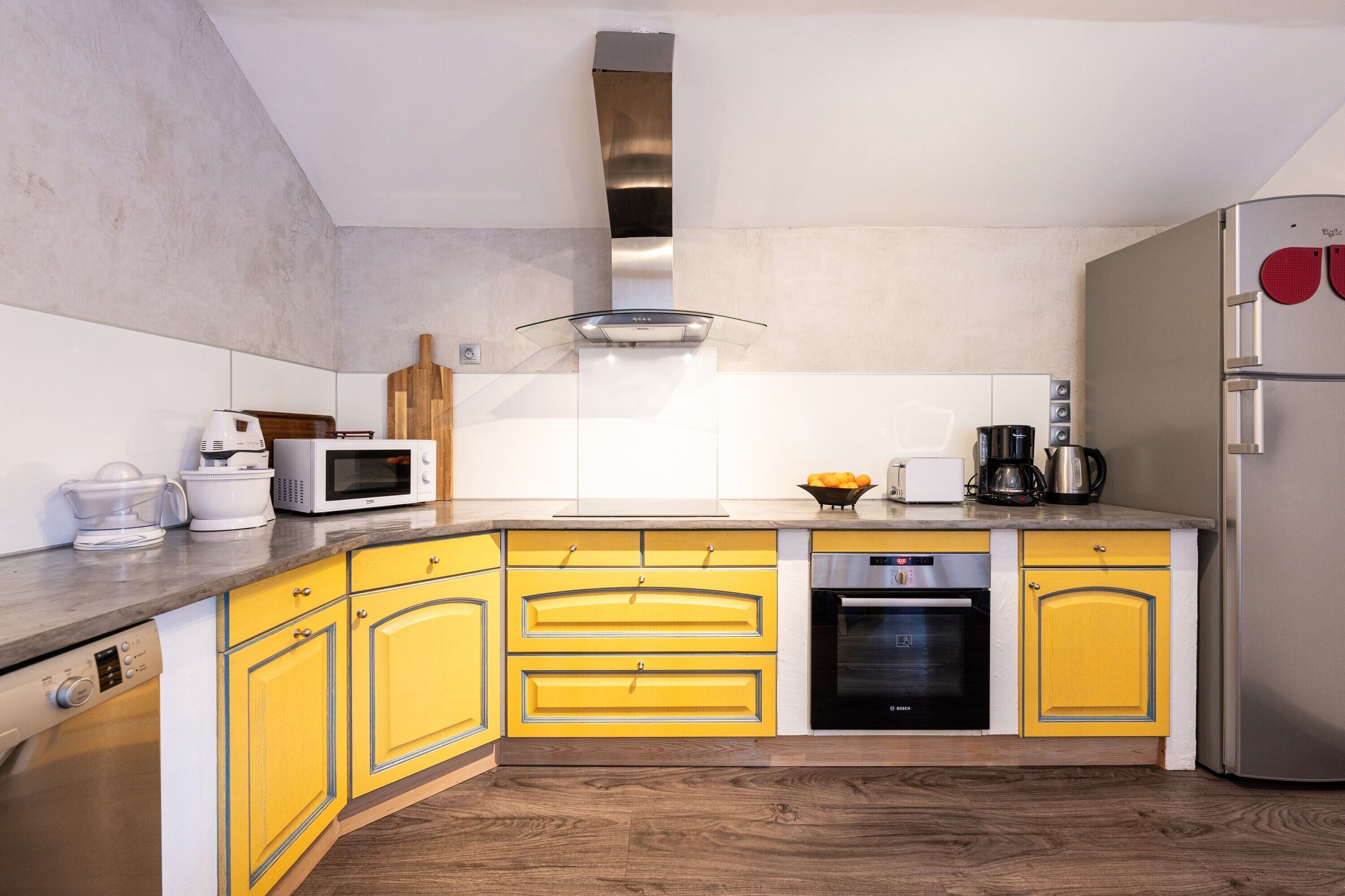 A modern kitchen with yellow cabinets, stainless steel appliances, and a wooden countertop.
