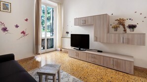 Una sala de estar con televisor, armarios de madera, sofá y alfombra estampada.
