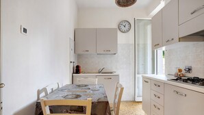 Una cocina con una mesa de comedor, sillas, armarios, un reloj y una estufa.