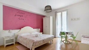 A bedroom with a bed, a nightstand, a dresser, a desk with a chair, and a window with curtains. - Room 'Camera Rosa' with Balcony, Wi-Fi and Air Conditioning (Riomaggiore)
