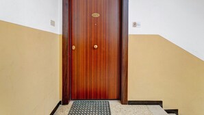 A wooden door with a brass handle and a nameplate, a step with a metal mat, and a wall with a number sign. - Room 'Camera Rosa' with Balcony, Wi-Fi and Air Conditioning (Riomaggiore)