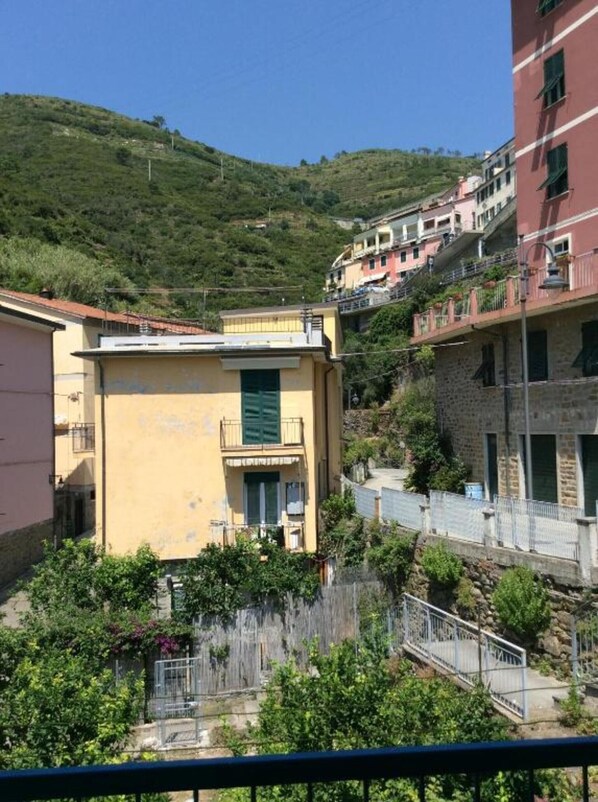 A hillside residential area with buildings, a small bridge, and greenery.