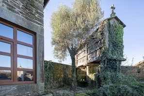 A stone building with a large window and a tree in front.