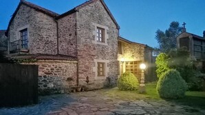 Ein Gebäude aus Stein mit traditioneller Gestaltung, einem gepflasterten Innenhof und einem kleinen Garten.