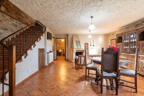 Une pièce spacieuse avec un escalier en bois, un coin repas comprenant une table et des chaises, et une cheminée en pierre.