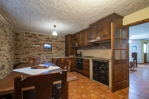 Une cuisine rustique avec des murs en pierre, des armoires en bois et un sol carrelé.