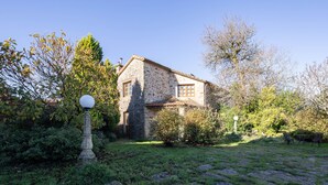 Ein Steinhaus mit Garten, einer Lampe und einer Bank.