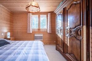 A wooden-paneled room with a bed, a wardrobe, and a window with curtains.
