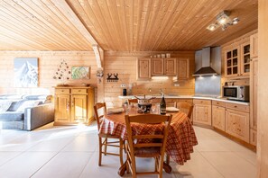 A wooden cabin interior with a dining area, kitchen, and living space.