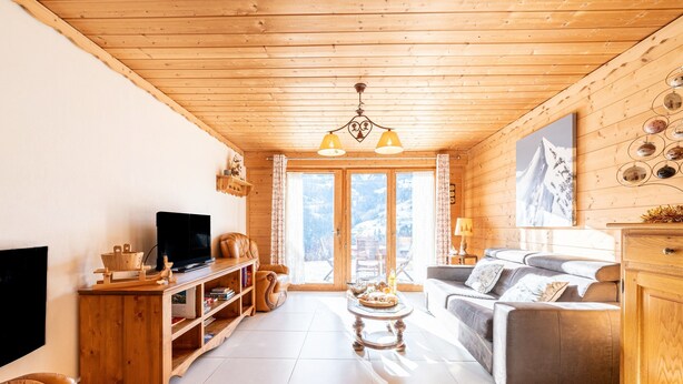 Un interior de madera con televisor, sofá y mesa de centro.