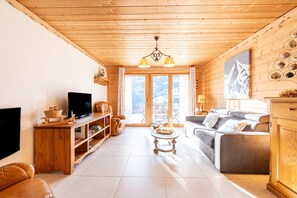 A wooden interior with a television, sofa, and coffee table. - Chalet 'Tié No Appartement Chaleureux' with Mountain View, Private Terrace and Wi-Fi (Manigod)