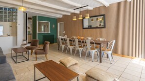 A modern dining area with a wooden accent wall, a large mirror, and a dining set. - Gîte 'Le Cottage' with Shared Pool, Private Terrace and Wi-Fi (Saint-Romain-de-Benet)
