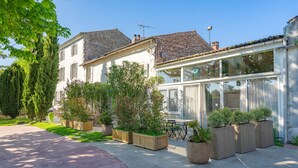 A residential property with a covered patio, potted plants, and a clear sky. - Gîte 'Le Cottage' with Shared Pool, Private Terrace and Wi-Fi (Saint-Romain-de-Benet)