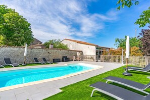 A swimming pool with lounge chairs and a stone wall.